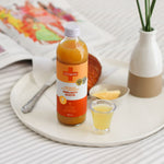 Bottle of Turmeric Daily Good Immunity Shots alongside breakfast and magazine 